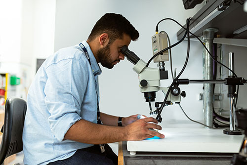 Biomedical Engineer Looking Into A Microscope